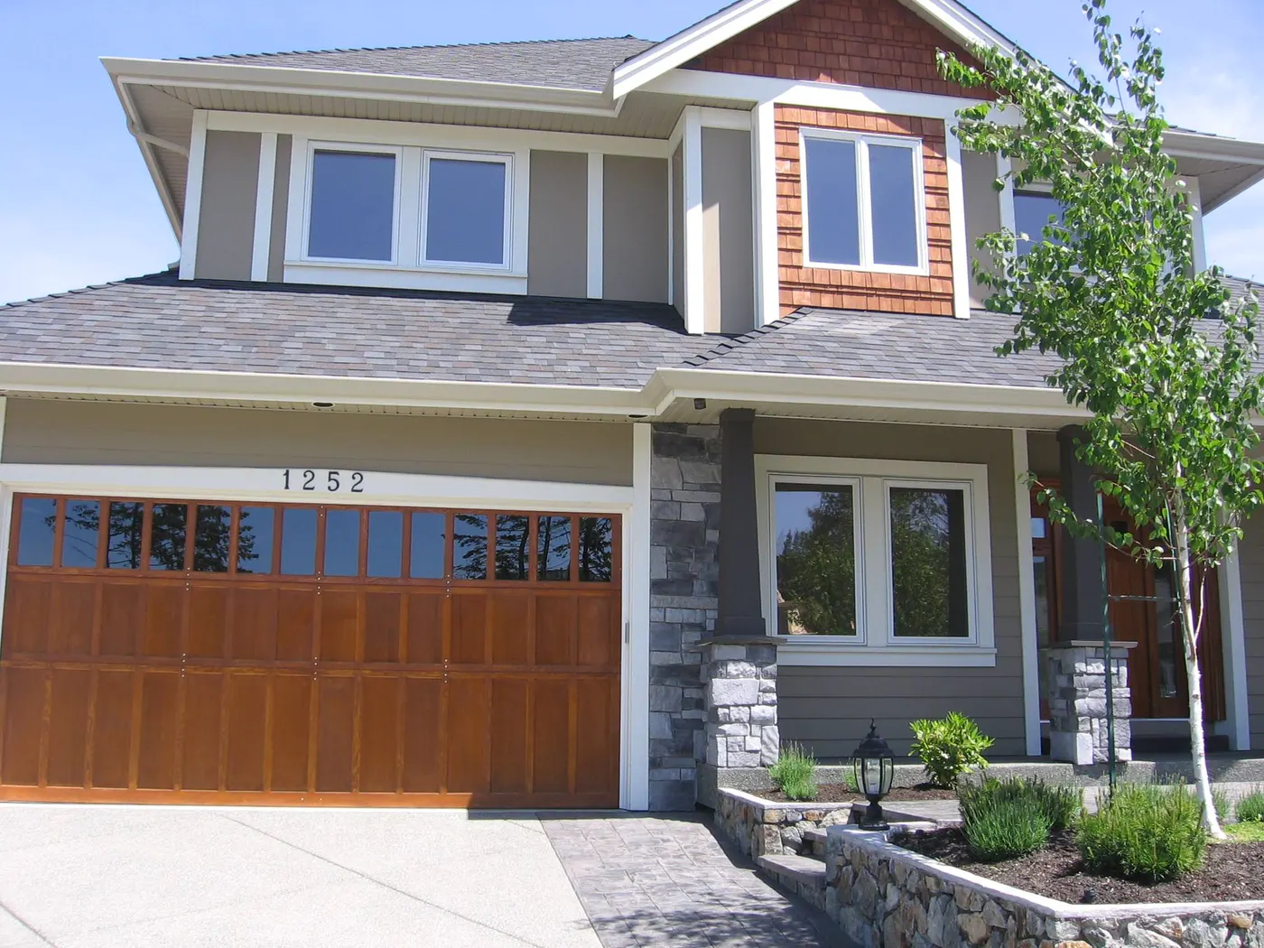 Craftsman custom home with wood garage door and stone details