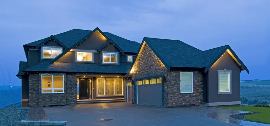 Custom home at dusk with stone exterior and lit windows — Dev Dheenshaw Construction
